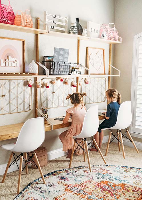 Two small girls sitting on the chairs and studying