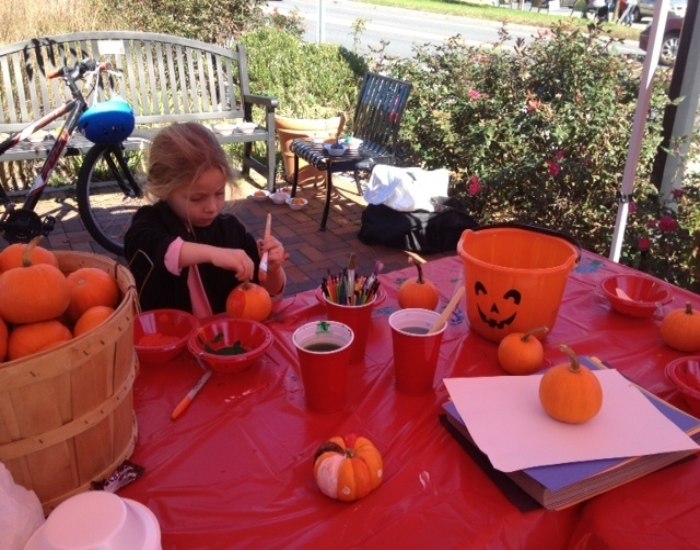 A small girl painting pumpkin