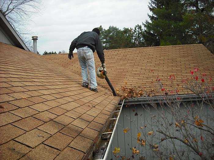 Man cleaning the roof of a house